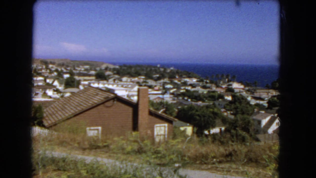 Coastal homes and streets on a hillside with the ocean visible in the background.
