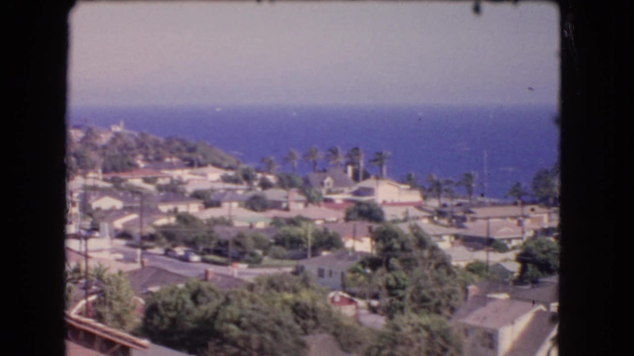 Los Angeles coastal hillside neighborhood in 1966, showing clustered homes, palm trees, and ocean beyond the rooftops.