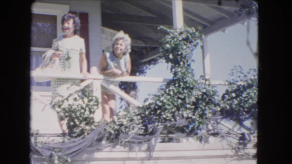 Two women in summer clothing stand on a vine-covered porch in 1966 Los Angeles home-movie footage.