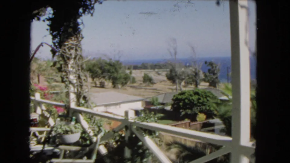 1966 Los Angeles-area 8mm view from a balcony over coastal homes, palms, garden plants, and the ocean horizon.