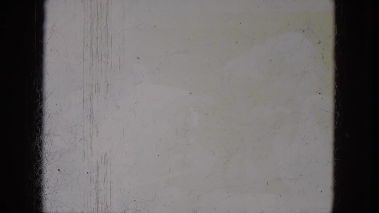 Blank or overexposed 8mm frame area with visible gate borders, dust, scratches, and aged yellow staining.