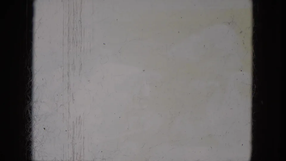Blank or overexposed 8mm frame area with visible gate borders, dust, scratches, and aged yellow staining.