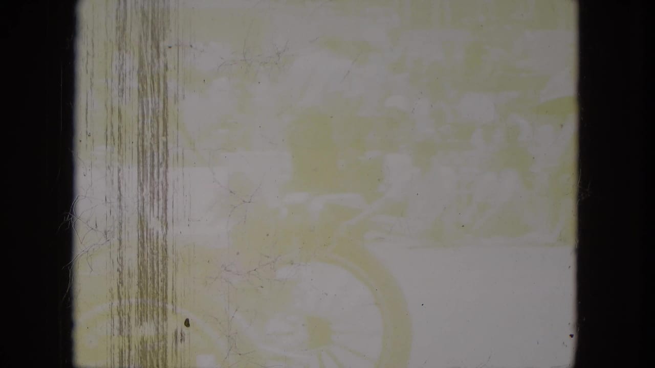 Aged 8mm frame with little visible scene detail, showing scratches, dust, gate edges, and yellow color cast.