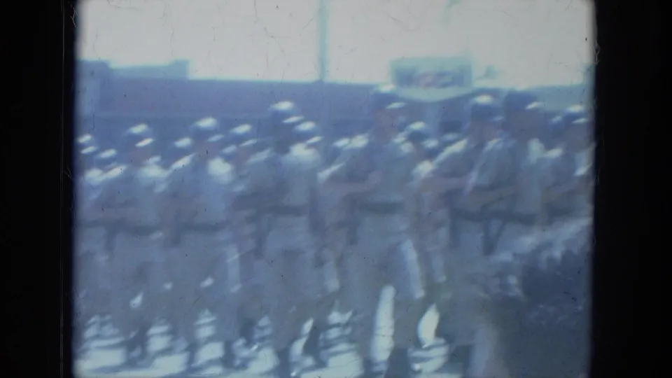 Soft, motion-blurred 8mm frame of soldiers marching in formation during the Milwaukee parade.