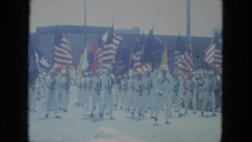 Sailors and other parade participants carry American flags and banners past spectators in Milwaukee, 1966.