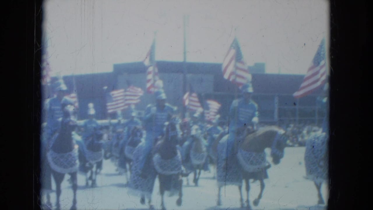 Mounted parade unit in Milwaukee, 1966, with American flags raised above horses and spectators visible behind them.