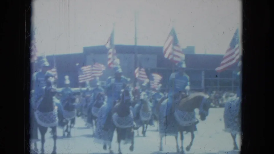 Mounted parade unit in Milwaukee, 1966, with American flags raised above horses and spectators visible behind them.