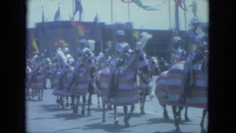 Milwaukee 1966 home-movie frame showing multiple decorated horses and costumed riders in a street parade with flags behind them.