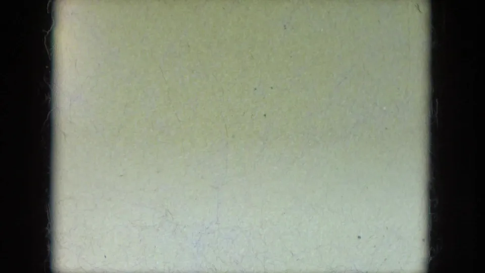 Mostly washed-out 8mm frame with pale exposure, visible grain, and a dark vertical gate edge; no person is clearly visible.