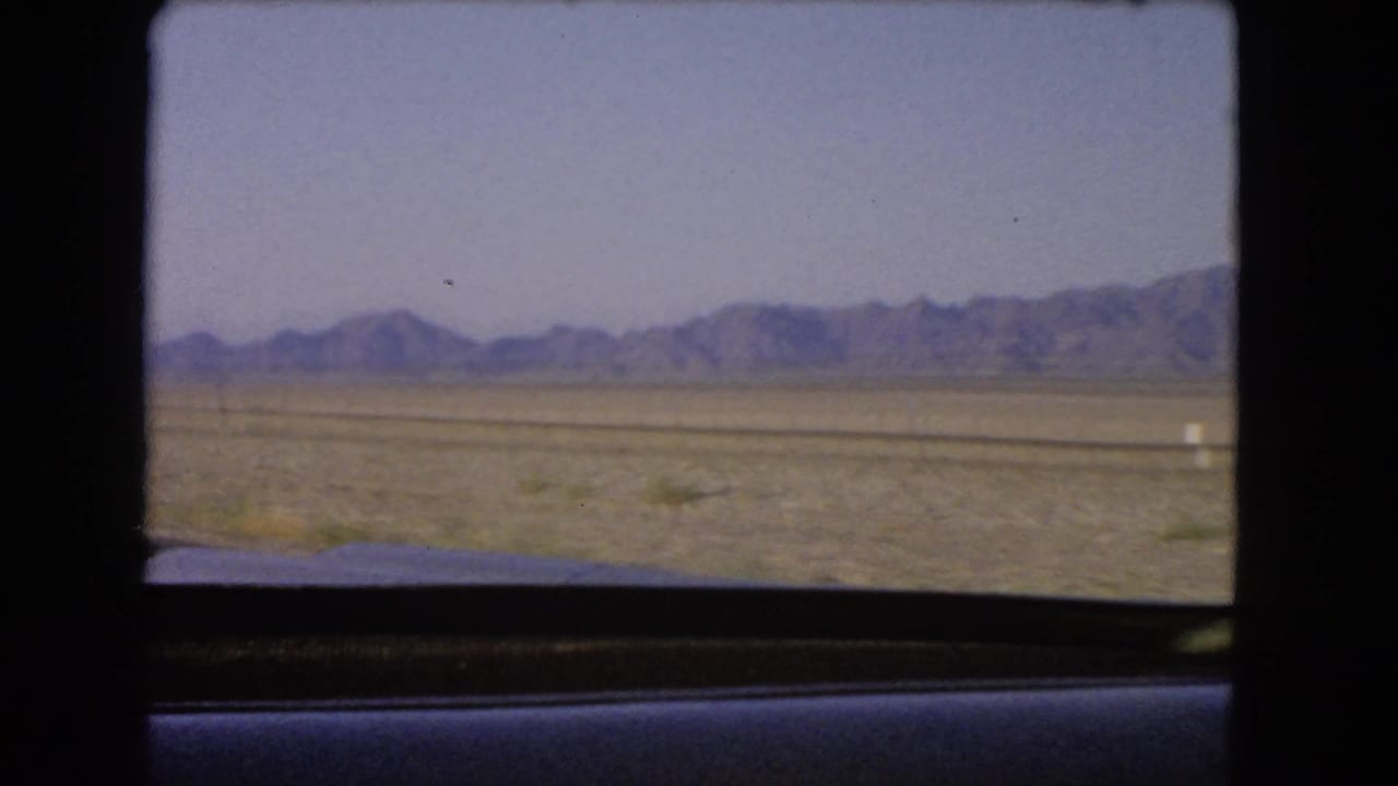 Nevada desert plain and distant mountains seen from inside a moving vehicle near the end of the clip.