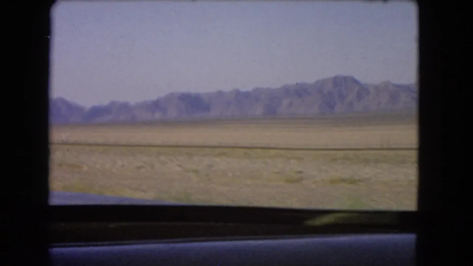 Nevada mountain range and open desert plain seen from inside a moving vehicle in 1966 home-movie footage.