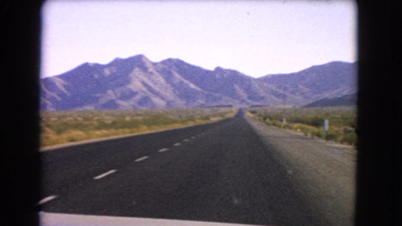 1966 Nevada 8mm frame showing a two-lane highway stretching through desert scrub toward low mountains.