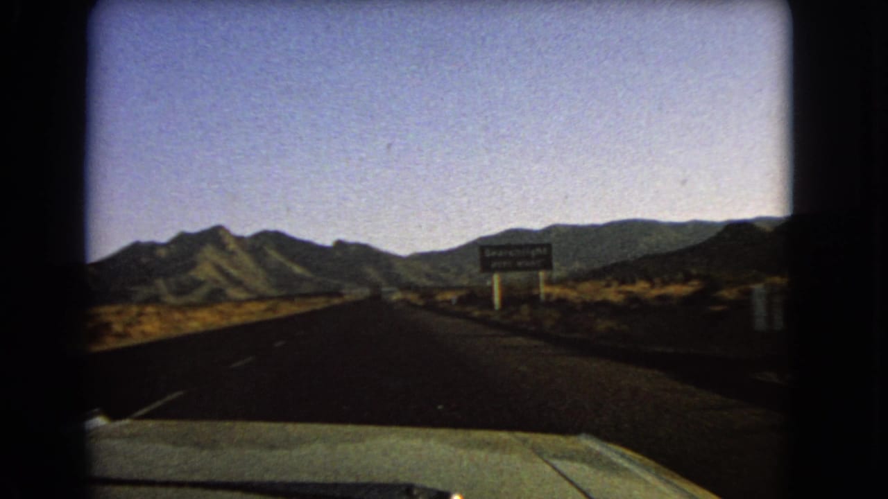 Desert highway view with the Searchlight next-right sign closer on the right shoulder.