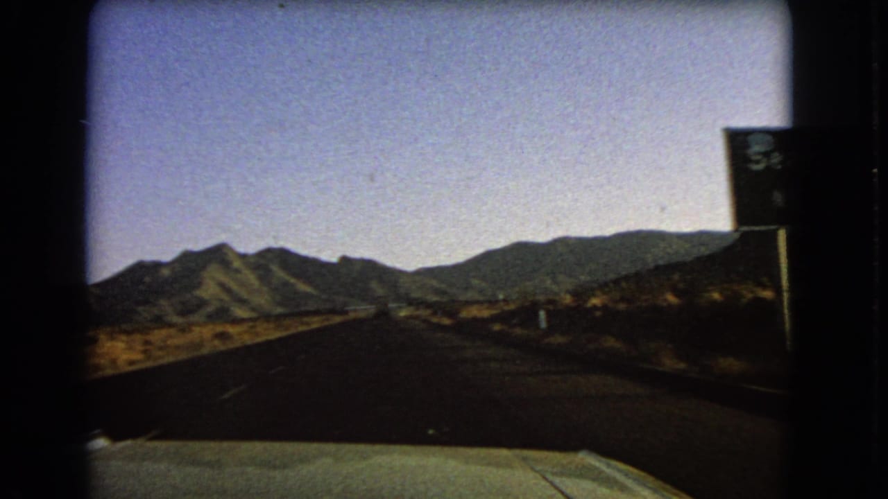 Nevada desert highway view after passing the Searchlight sign, with the road stretching toward low mountains.