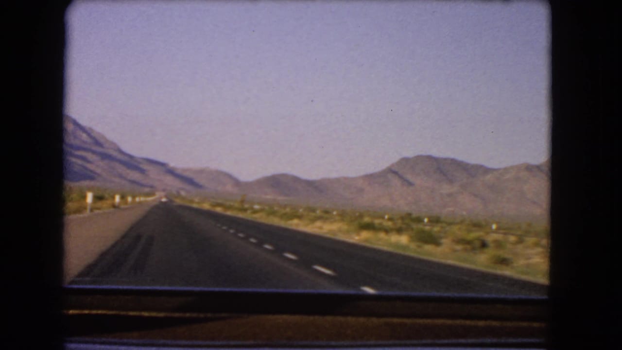 1966 Nevada 8mm frame showing a straight asphalt highway through desert scrub toward distant mountains.
