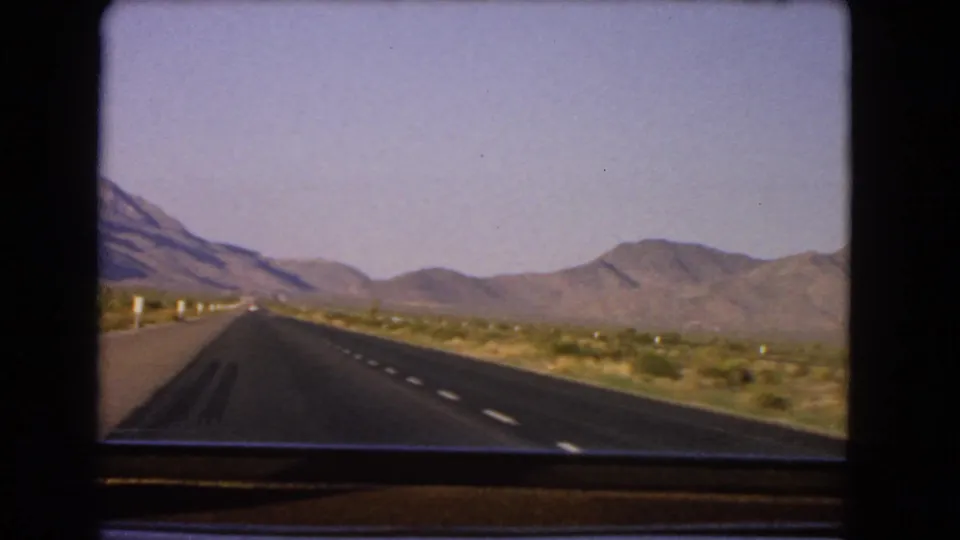 1966 Nevada 8mm frame showing a straight asphalt highway through desert scrub toward distant mountains.