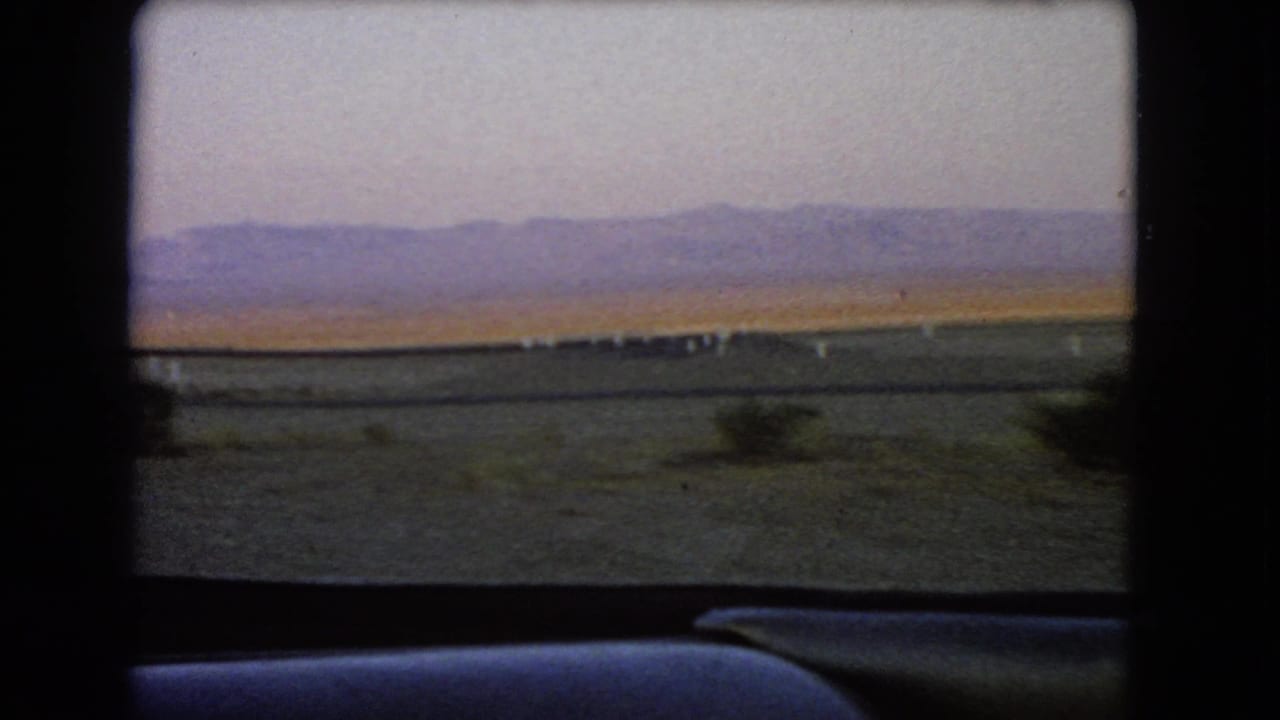Car interior frames a desert view with mountains on the horizon.