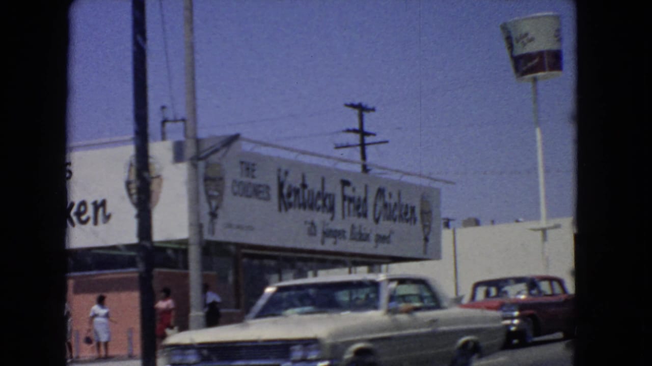1966 San Pedro side view of a Kentucky Fried Chicken building, pedestrians, period cars, utility poles, and bucket sign.