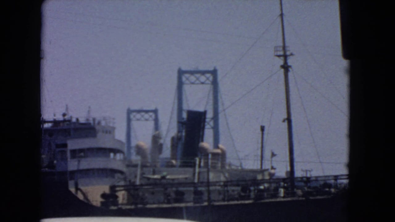 Faded 8mm frame from San Pedro showing a ship against a raised drawbridge and waterfront infrastructure.