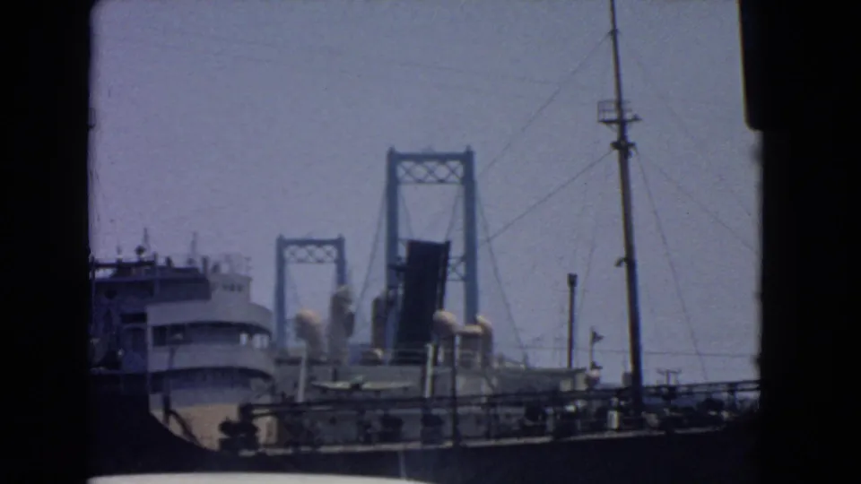 Faded 8mm frame from San Pedro showing a ship against a raised drawbridge and waterfront infrastructure.