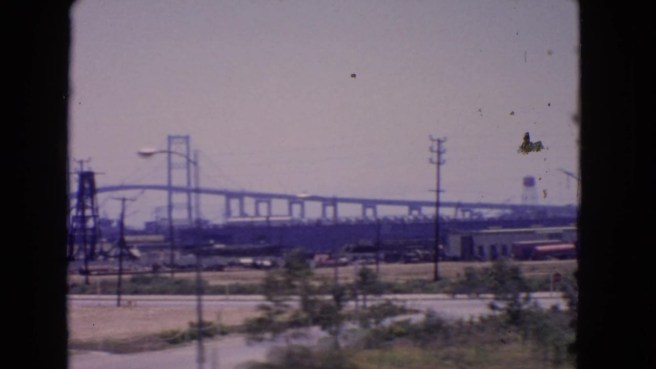Long view of Vincent Thomas Bridge with poles, yards, and industrial structures.