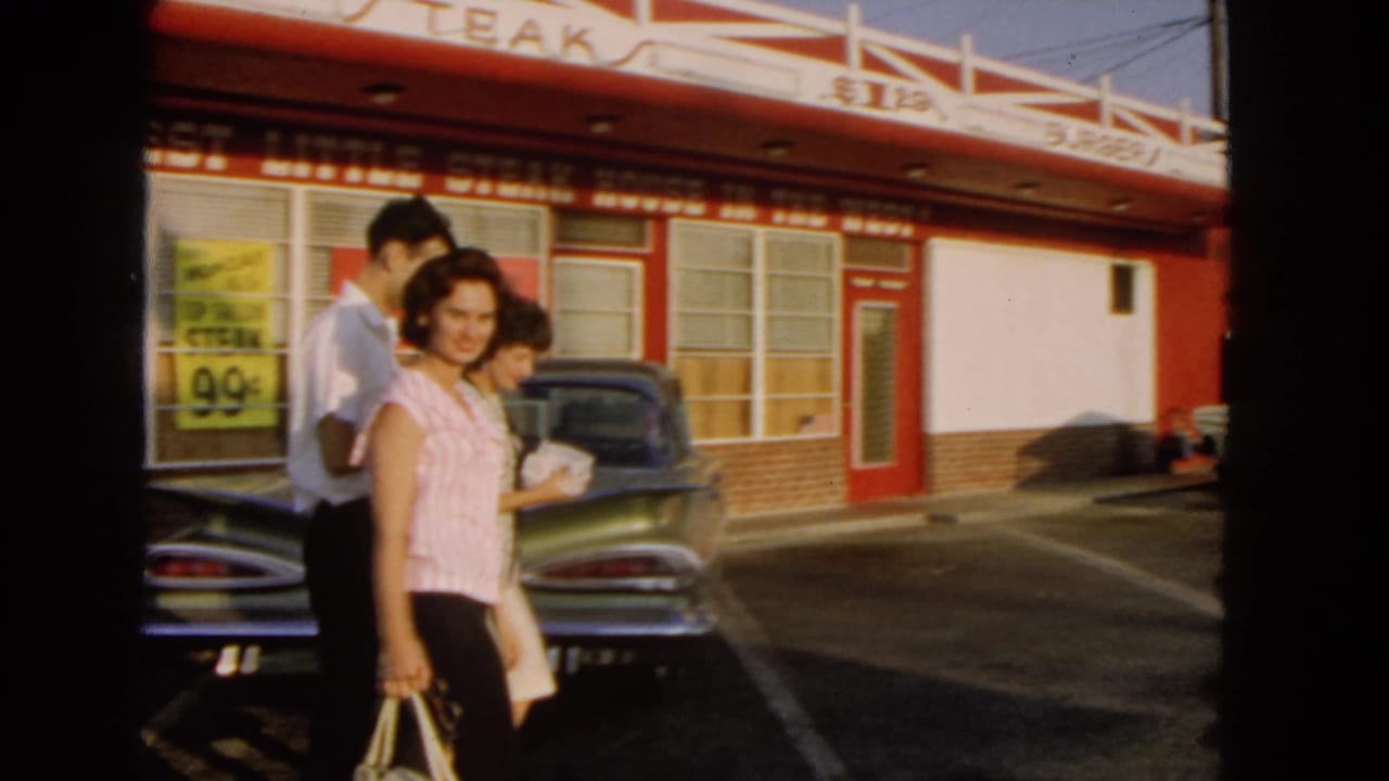 1966 San Pedro home-movie frame showing adults walking in front of a red-and-white diner and parked midcentury cars.