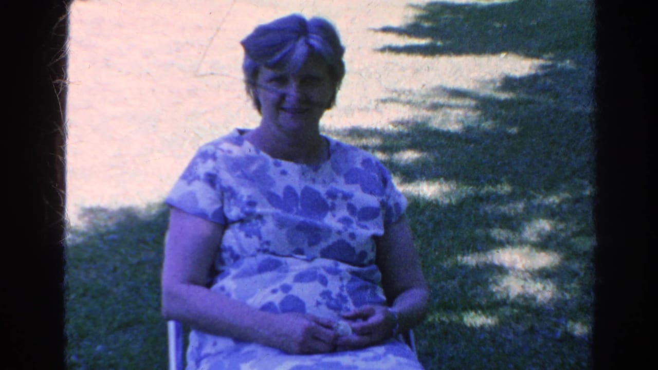 The woman remains seated in the Silver Lake garden setting, smiling gently toward the home-movie camera.