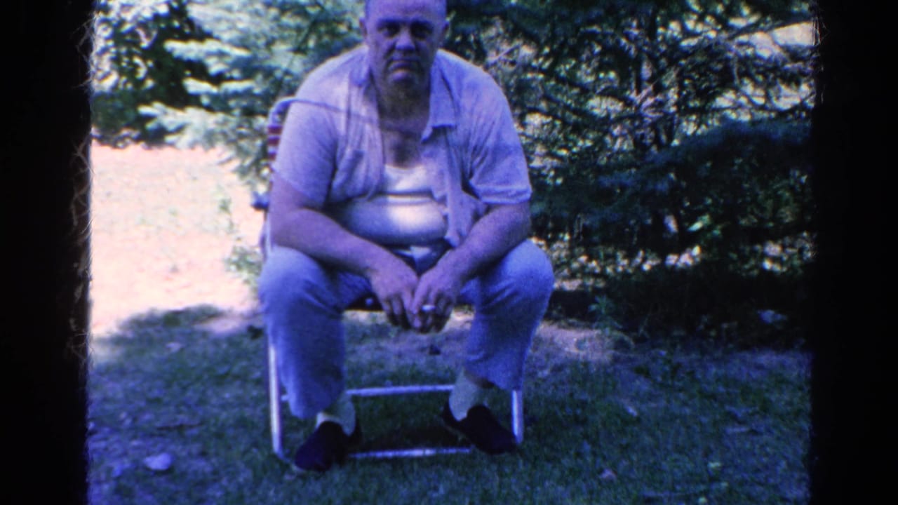 Man facing forward on a folding chair with trees behind him.