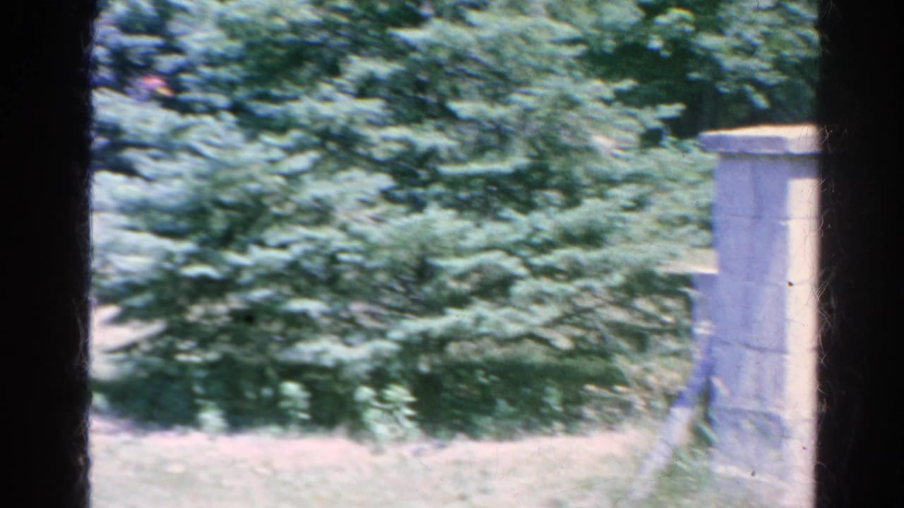 The camera passes across trees and lawn toward a pale stone pillar in the Silver Lake outdoor setting.