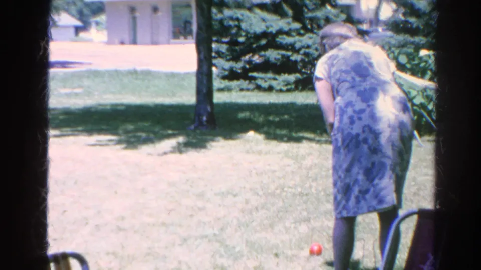 A woman prepares near a red croquet ball on the lawn in 1966 Silver Lake backyard home-movie footage.