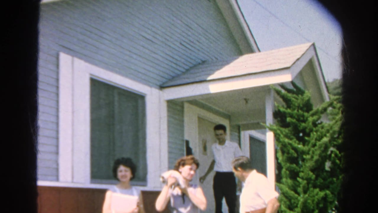 A woman holding a cat stands outside the doorway while two men and another woman are nearby.