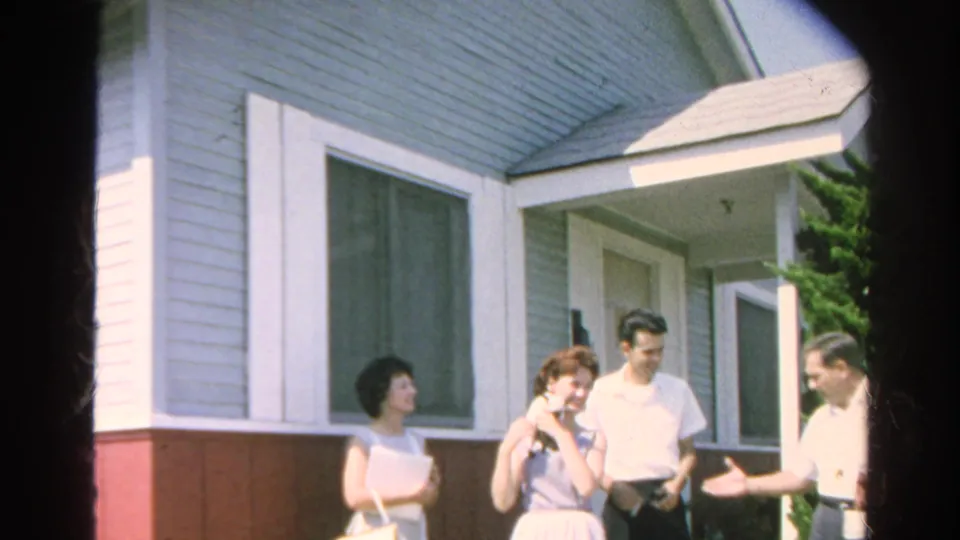 Four adults converse outside the Silver Lake residence in 1966, framed by the front door, large window, and evergreen shrub.