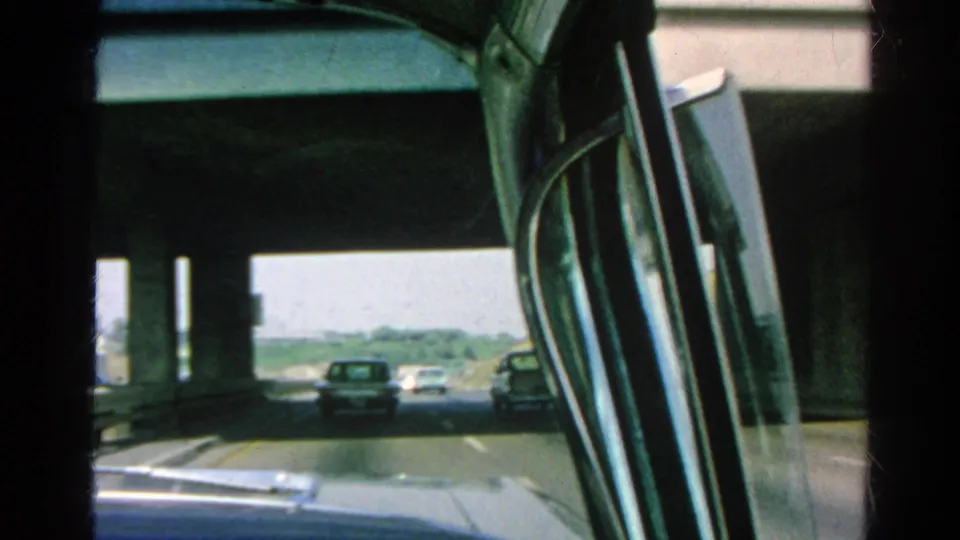 1966 Silver Lake-area freeway drive filmed through a passenger window as several cars pass beneath a concrete overpass.