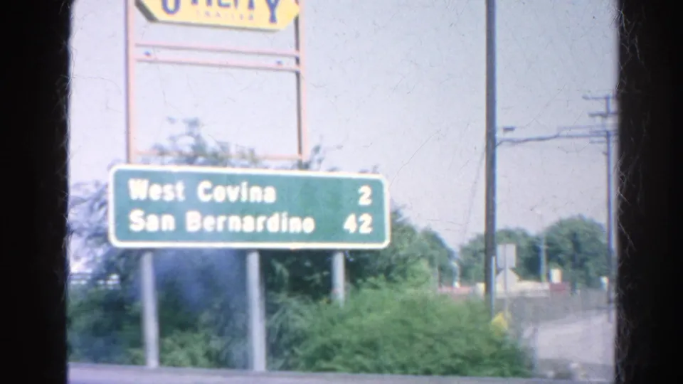 1966 Southern California roadside sign view showing distances to West Covina and San Bernardino beneath a Union 76-style sign.
