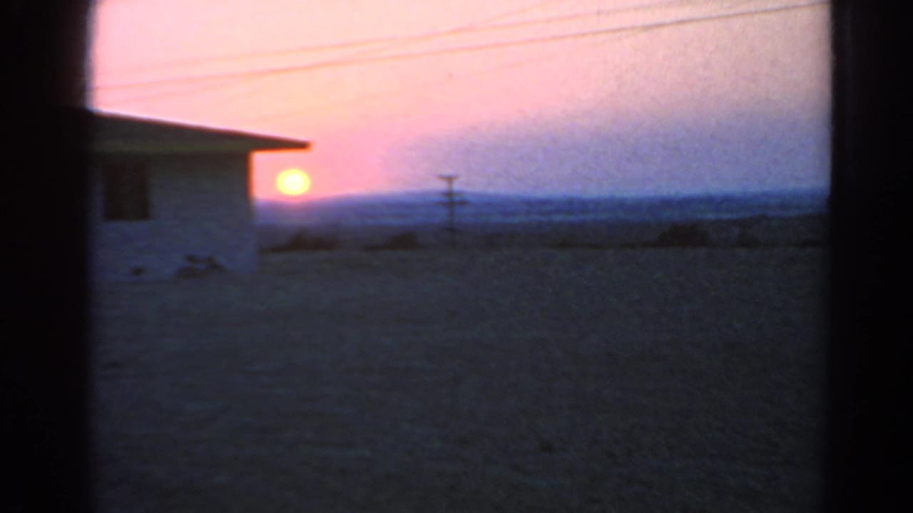 1966 Silver Lake 8mm frame with the sun low beside a white house, overhead wires, open ground, and soft dusk color.