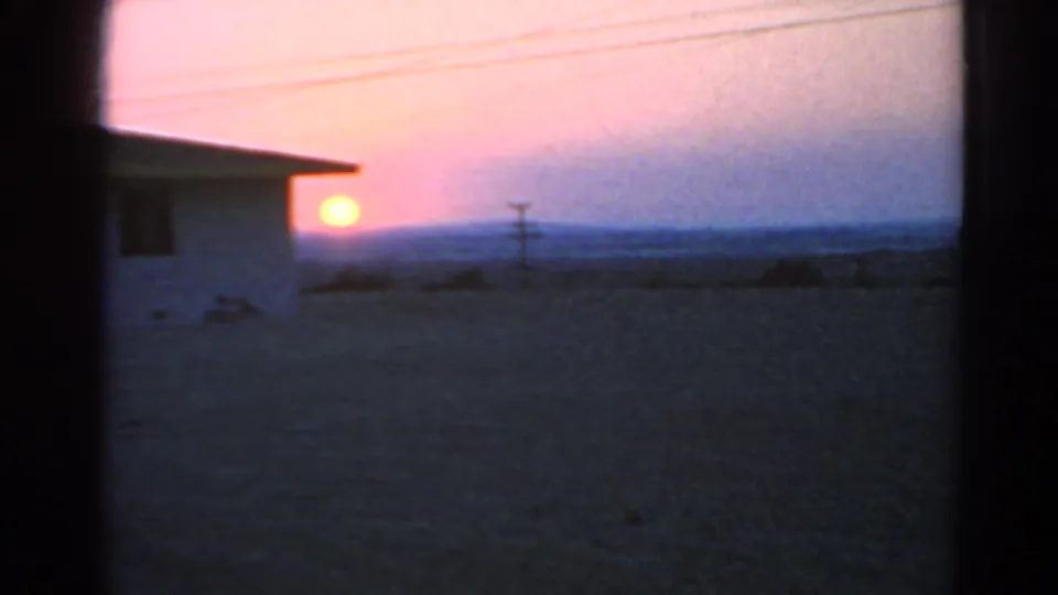 1966 Silver Lake 8mm frame with the sun low beside a white house, overhead wires, open ground, and soft dusk color.