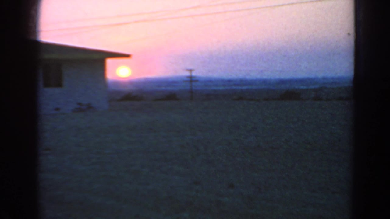 1966 Silver Lake frame showing a white house at sunset, utility pole, overhead wires, and open land in soft 8mm color.