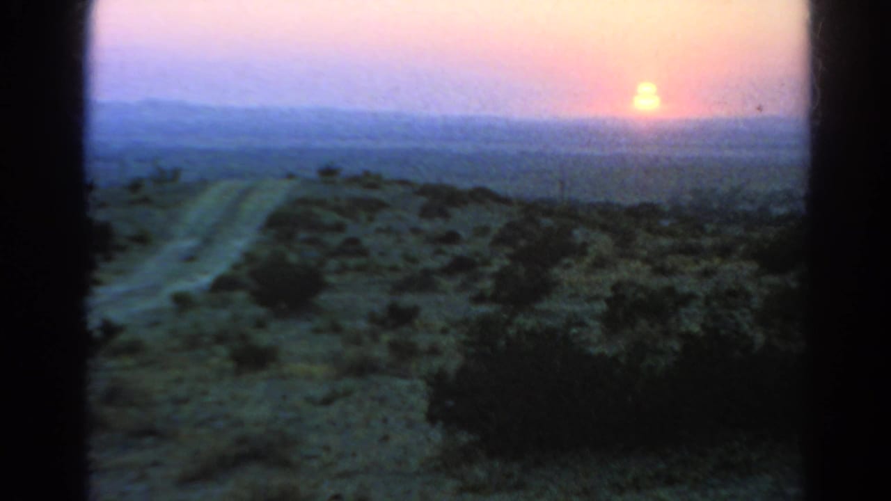1966 8mm home-movie frame of a dirt road running through arid scrub toward a low sunset in the Silver Lake, California metadata context.