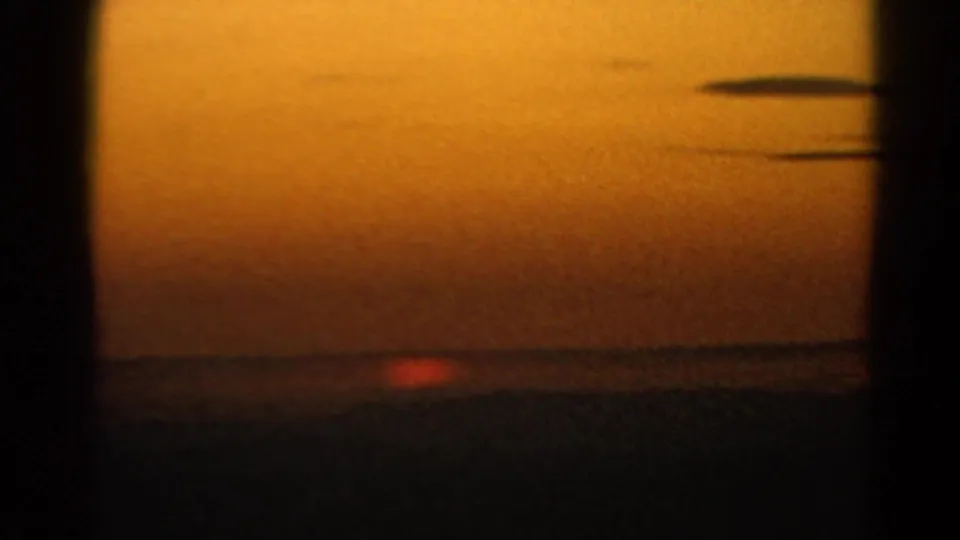 1966 Silver Lake home-movie frame showing a red-orange sun near the horizon under a warm sky and dark cloud streaks.