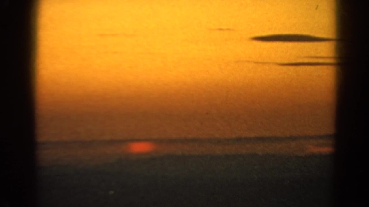 1966 Silver Lake sunset frame with a small red sun at the horizon, long dark clouds, and visible 8mm grain.