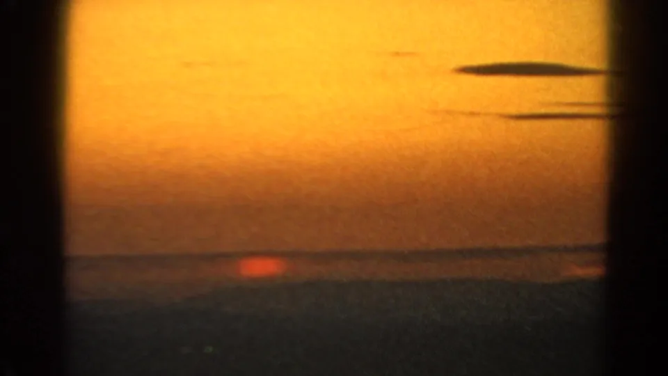 1966 Silver Lake sunset view with the sun near the waterline, orange sky, dark surface, and visible 8mm frame-edge shadowing.