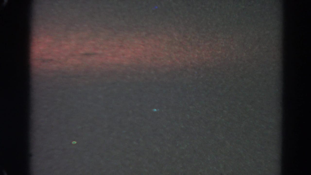 Late 1966 Silver Lake sunset frame with dim water, a faint warm horizon band, and pronounced 8mm grain.