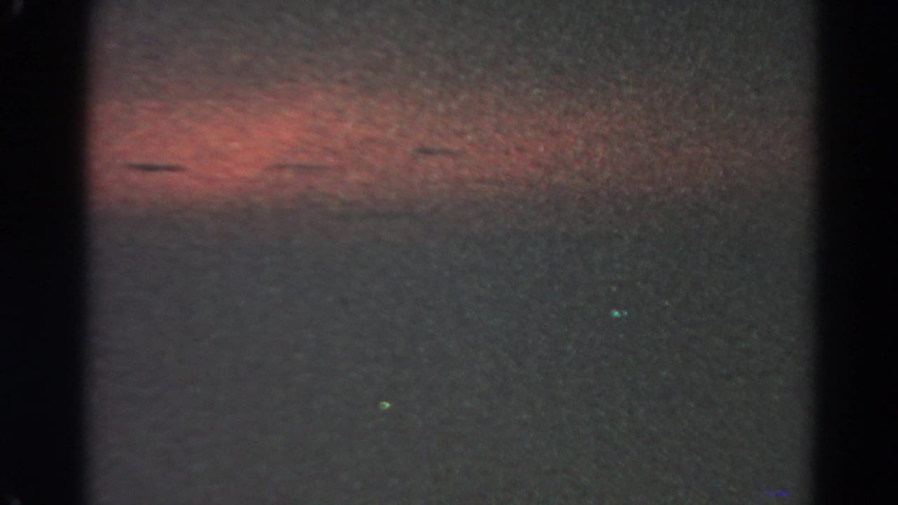 Dark sky with a red-orange band near the top and faint green light points below.