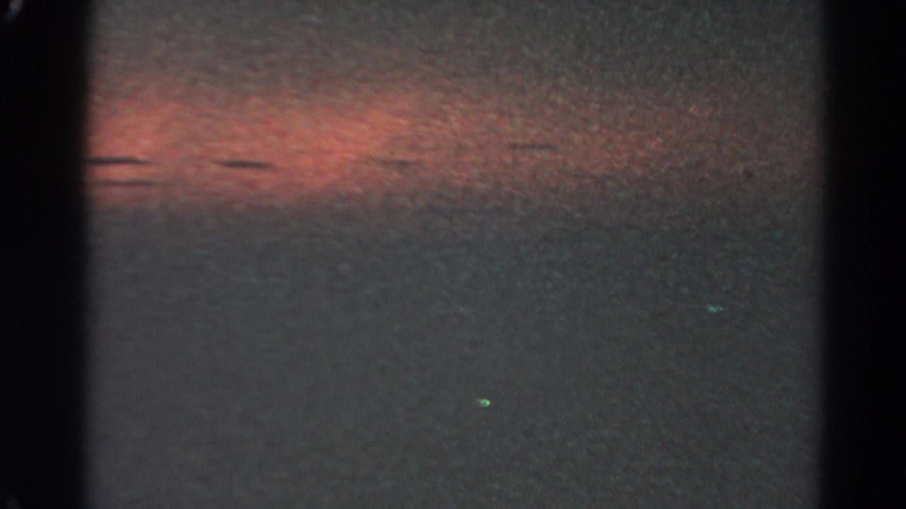 1966 Silver Lake 8mm frame showing the reddish night glow lower in the view, with black frame edges and small colored light specks.