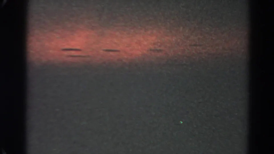 1966 Silver Lake night-sky frame with a broad red glow, faint colored points, dark borders, and pronounced 8mm grain.