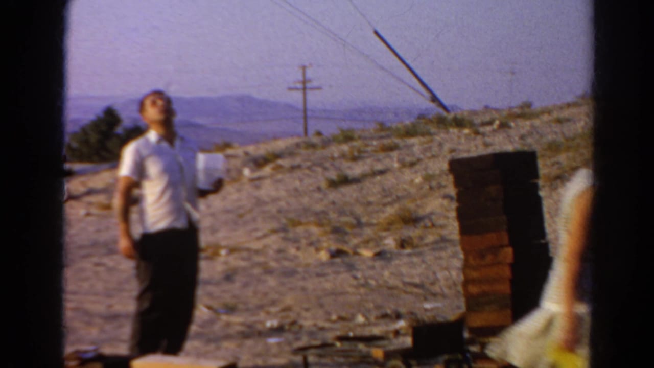 The man looks upward near a stack of bricks while the woman moves out of frame at the Silver Lake construction site.
