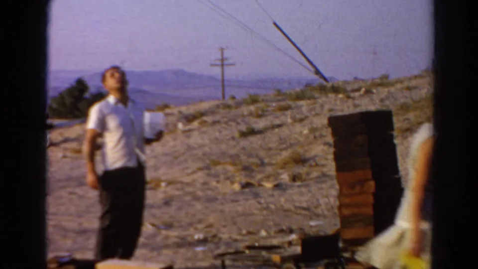 The man looks upward near a stack of bricks while the woman moves out of frame at the Silver Lake construction site.