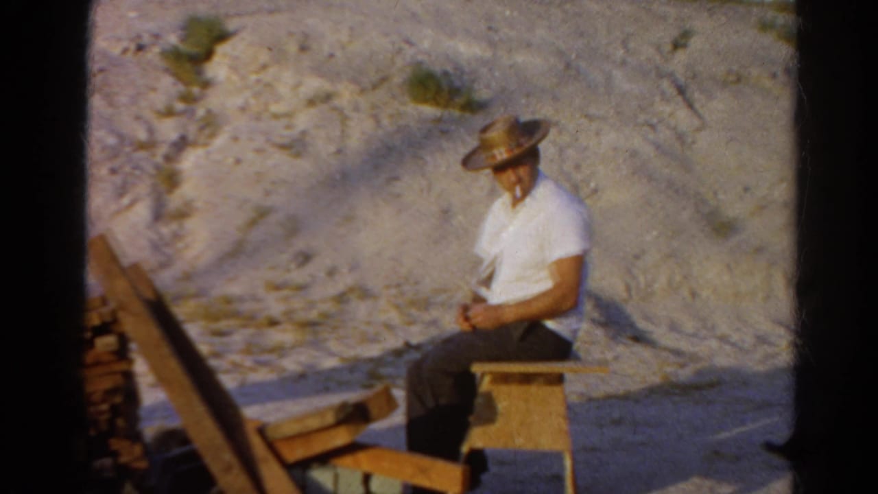 A 1966 Silver Lake frame shows the man seated quietly with his hat down, surrounded by wood and dirt slope.
