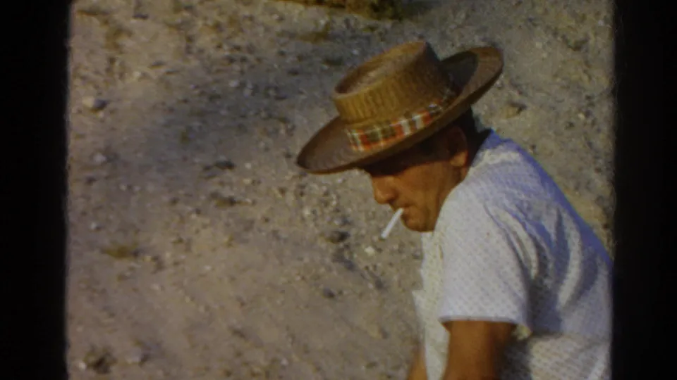 1966 Silver Lake frame with a man in profile wearing a straw hat and smoking beside a sunlit dusty slope.