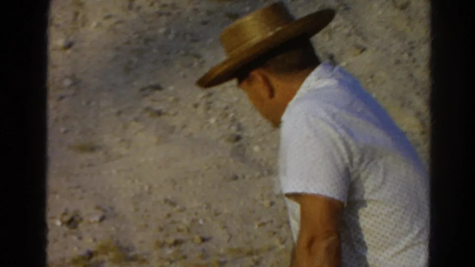 1966 Silver Lake frame showing the man turned away, his straw hat and white shirt silhouetted against the dry slope.